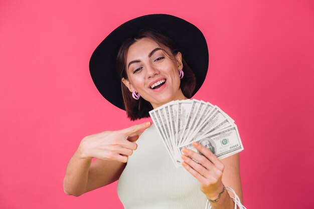 Mujer elegante con sombrero en la pared roja rosa