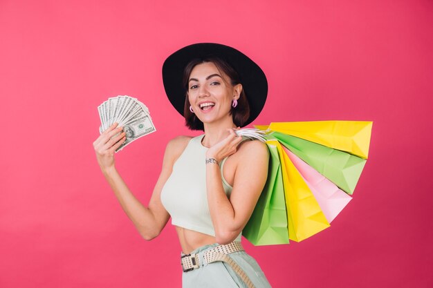 Mujer elegante con sombrero en la pared roja rosa