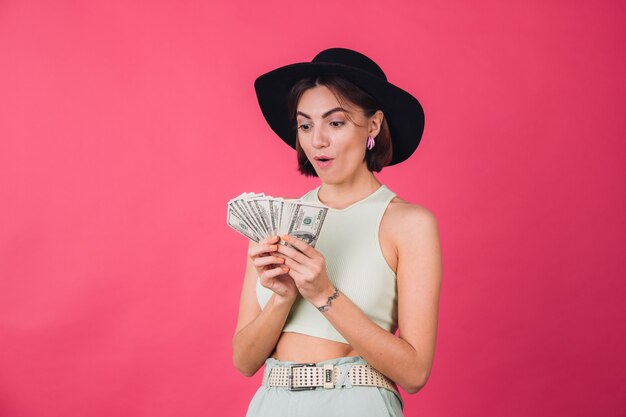 Mujer elegante con sombrero en la pared roja rosa