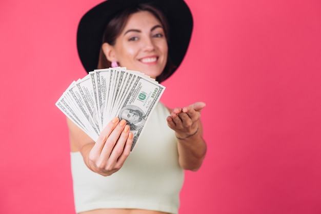 Mujer elegante con sombrero en la pared roja rosa