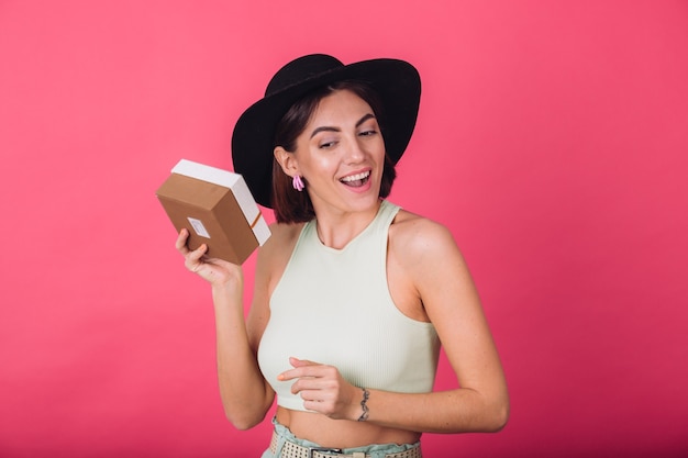 Mujer elegante con sombrero en la pared roja rosa