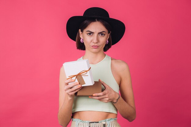 Mujer elegante con sombrero en la pared roja rosa