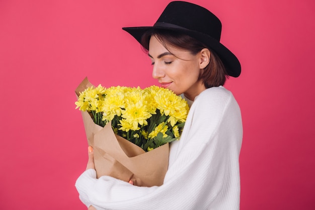 Mujer elegante con sombrero en la pared roja