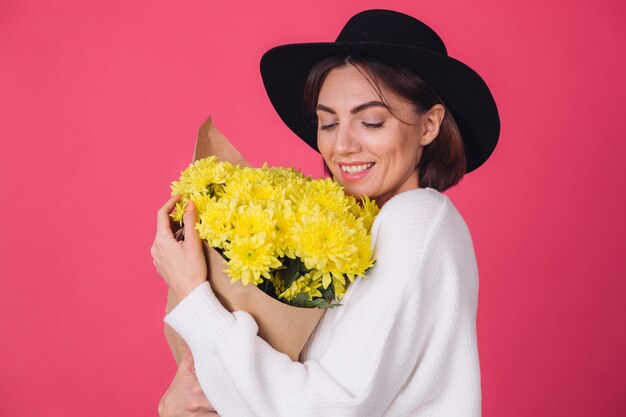 Mujer elegante con sombrero en la pared roja