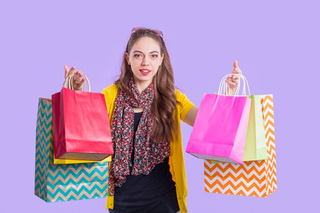 Mujer elegante sonriente que muestra la bolsa de papel colorida