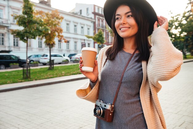 Mujer elegante sonriente que sostiene la taza de café