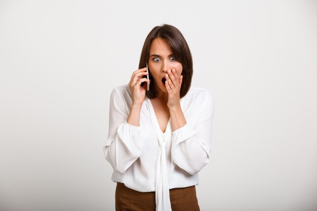 Mujer elegante sorprendida hablando por teléfono, cotilleando