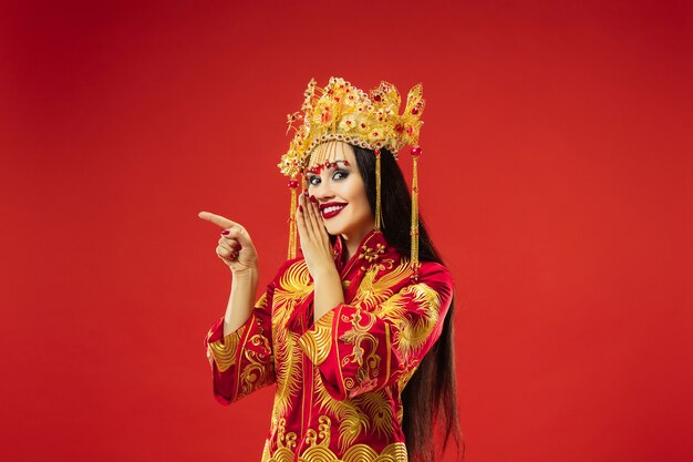 Mujer elegante tradicional china en el estudio sobre fondo rojo.