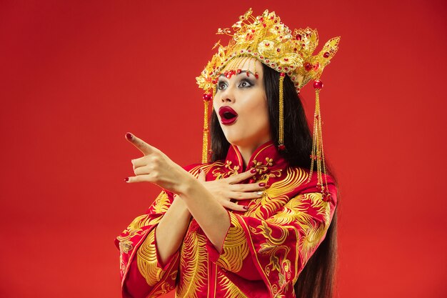 Mujer elegante tradicional china en el estudio sobre fondo rojo.