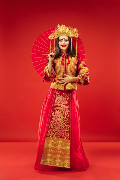 Mujer elegante tradicional china en el estudio sobre fondo rojo.