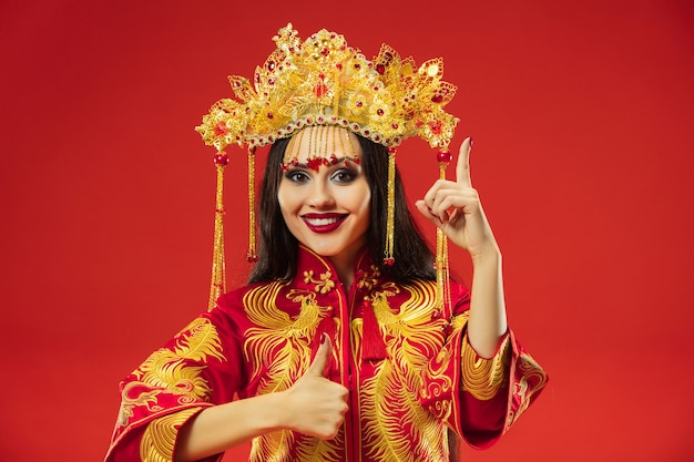Mujer elegante tradicional china en el estudio sobre fondo rojo.