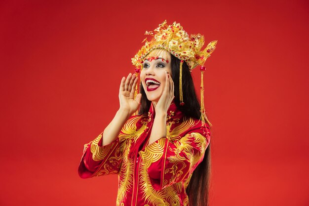 Mujer elegante tradicional china en el estudio sobre la pared roja