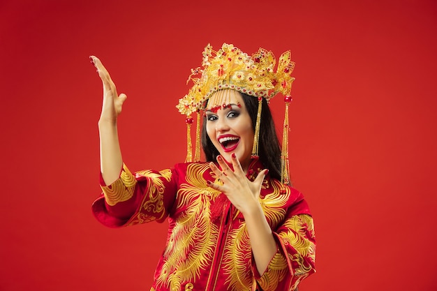 Mujer elegante tradicional china en el estudio sobre la pared roja