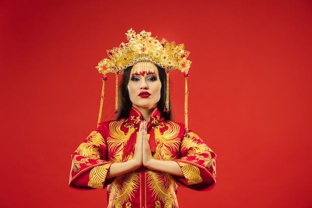 Mujer elegante tradicional china en el estudio sobre la pared roja