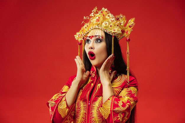 Mujer elegante tradicional china en el estudio sobre la pared roja