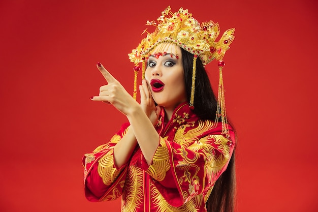 Mujer elegante tradicional china en el estudio sobre la pared roja