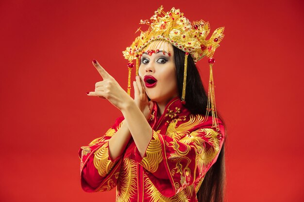 Mujer elegante tradicional china en el estudio sobre la pared roja