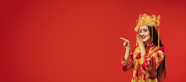 Mujer elegante tradicional china en el estudio sobre la pared roja