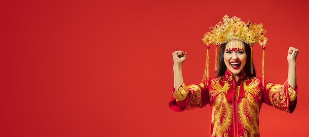 Mujer elegante tradicional china en el estudio sobre rojo.