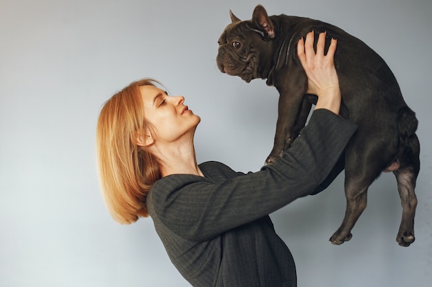 Mujer elegante en un traje negro con bulldog negro