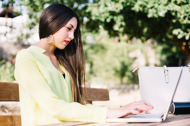 Mujer elegante usando laptop en el parque