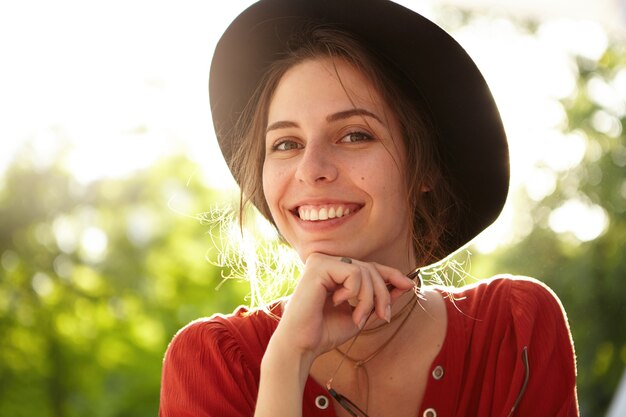 Mujer elegante vestida con blusa roja y sombrero grande