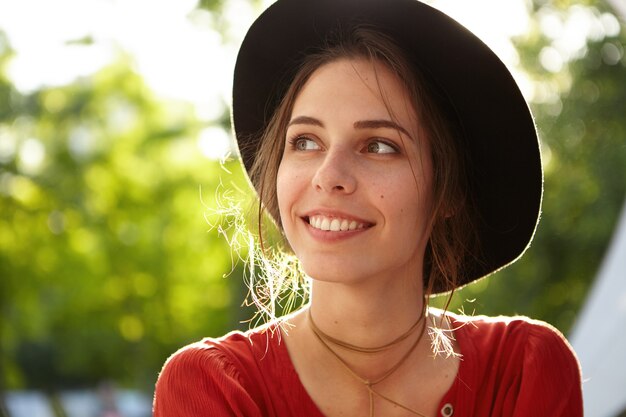 Mujer elegante vestida con blusa roja y sombrero grande