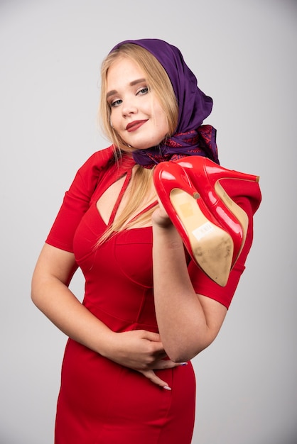 Mujer elegante en vestido rojo con par de tacones.