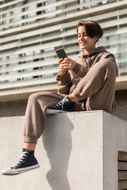 Mujer elegante vistiendo ropa deportiva y comprobando su teléfono