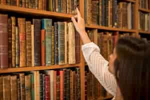 Foto gratuita mujer elegir libro de estantería en biblioteca