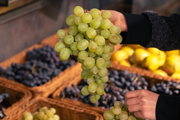 Foto gratuita una mujer elige uvas verdes en una tienda de comestibles