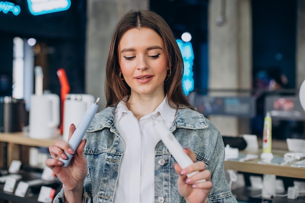 Mujer eligiendo cepillo de dientes eléctrico en la tienda