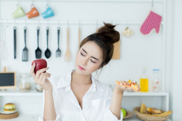 mujer eligiendo entre manzana y pizza