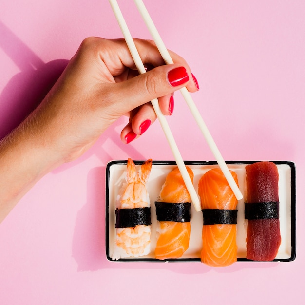 Mujer eligiendo un sushi del plato