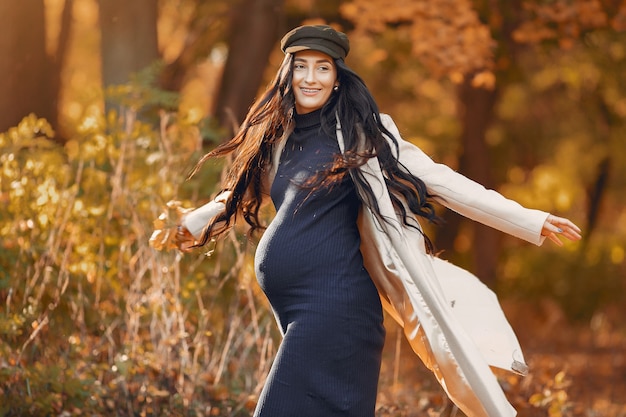 Foto gratuita mujer embarazada en un abrigo marrón en un parque de otoño