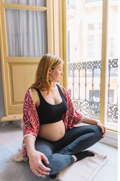Mujer embarazada al lado de ventana abierta
