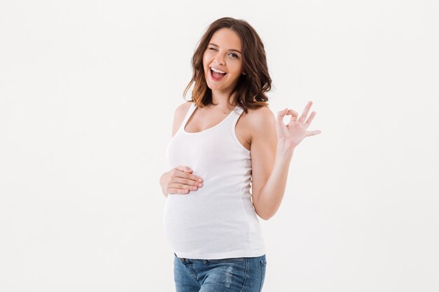 Mujer embarazada alegre que muestra gesto aceptable.