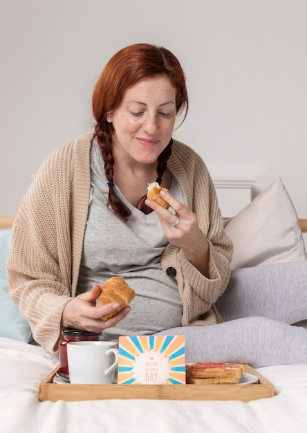 Mujer embarazada de alto ángulo disfrutando croissant