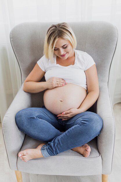 Mujer embarazada de alto ángulo sintiendo a su hijo