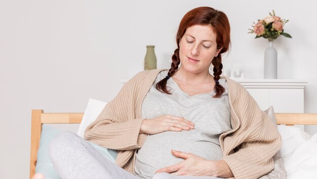 Mujer embarazada de ángulo bajo acostada en la cama
