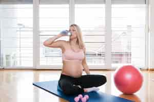 Foto gratuita mujer embarazada bebiendo agua en gimnasio