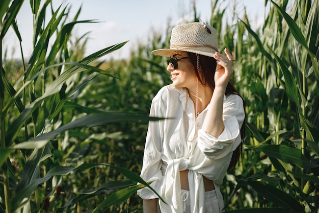 Mujer embarazada caminando en un campo de maíz. Mujer morena caminando en el campo de verano con ropa blanca
