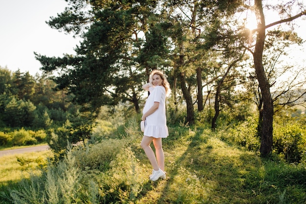 Mujer embarazada caminando en el parque con puesta de sol