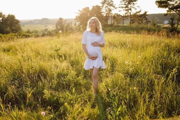 Mujer embarazada caminando en el parque con puesta de sol