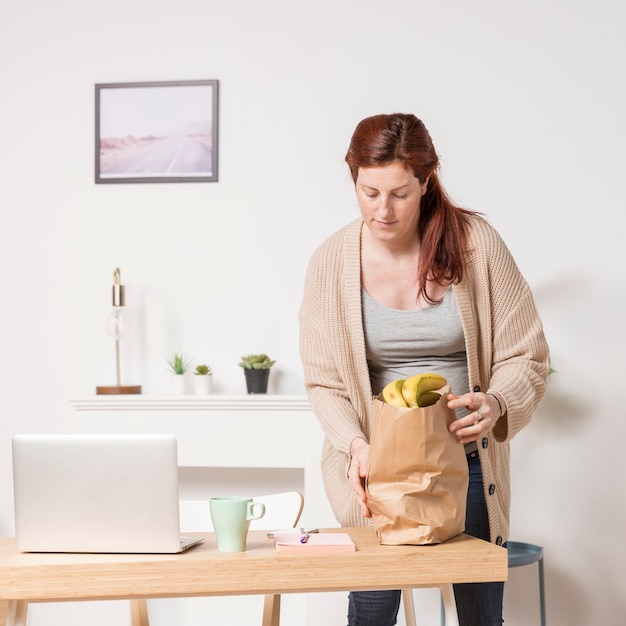 Foto gratuita mujer embarazada en casa con bolsa de supermercado