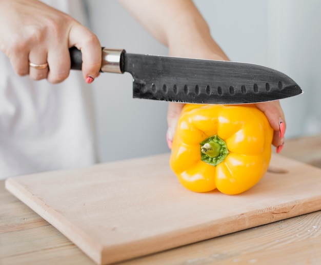 Foto gratuita mujer embarazada cortando un pimiento amarillo