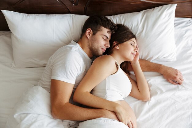 Mujer embarazada durmiendo en la cama con su esposo