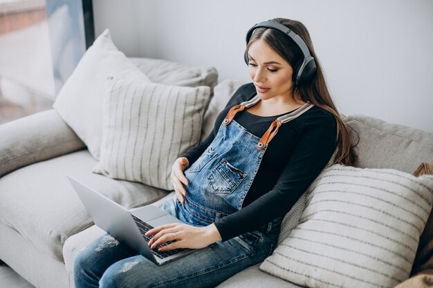 Mujer embarazada escuchando música en auriculares y navegando por internet