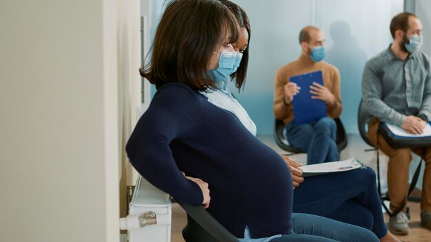 Mujer embarazada esperando en la cola para comenzar la entrevista de trabajo, preparando el archivo cv para la selección. Solicitante que espera un hijo y asiste a una reunión de empleo con el reclutador de recursos humanos, solicitud de empleo.