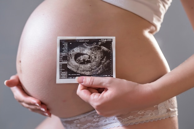 Mujer embarazada con foto de su futuro bebé